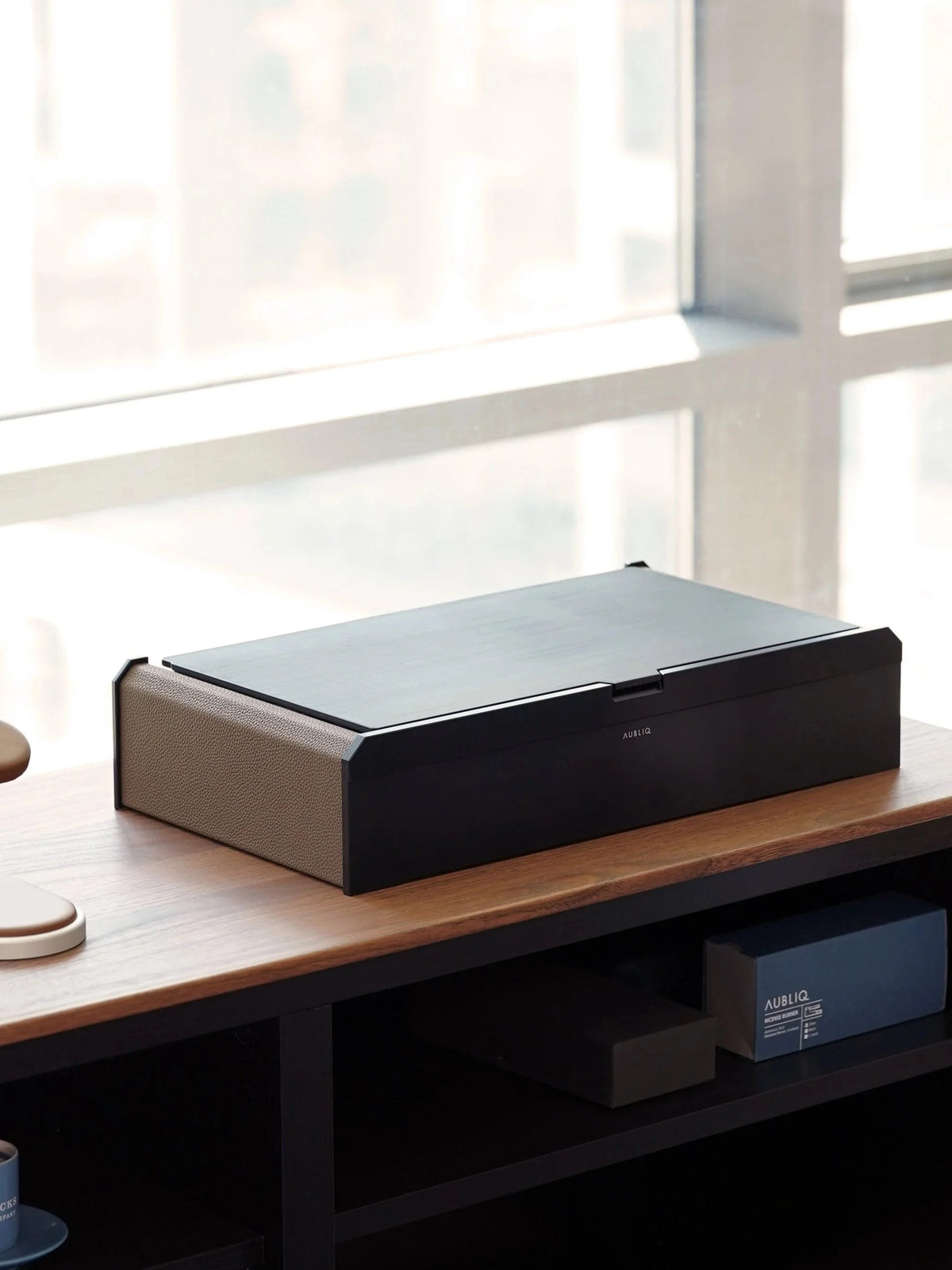 Coffret Aubliq Attention aluminium noir et cuir marron sur un meuble