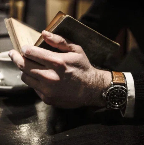 Homme lisant un livre, montre-bracelet élégante au poignet en cuir marron