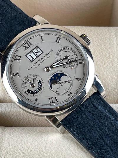 Montre de luxe à cadran argenté, chiffres romains, affichage phases de lune et grande date.