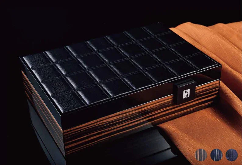 Coffret à montres luxe en cuir noir et bois, posé sur tissu orange, fond sombre